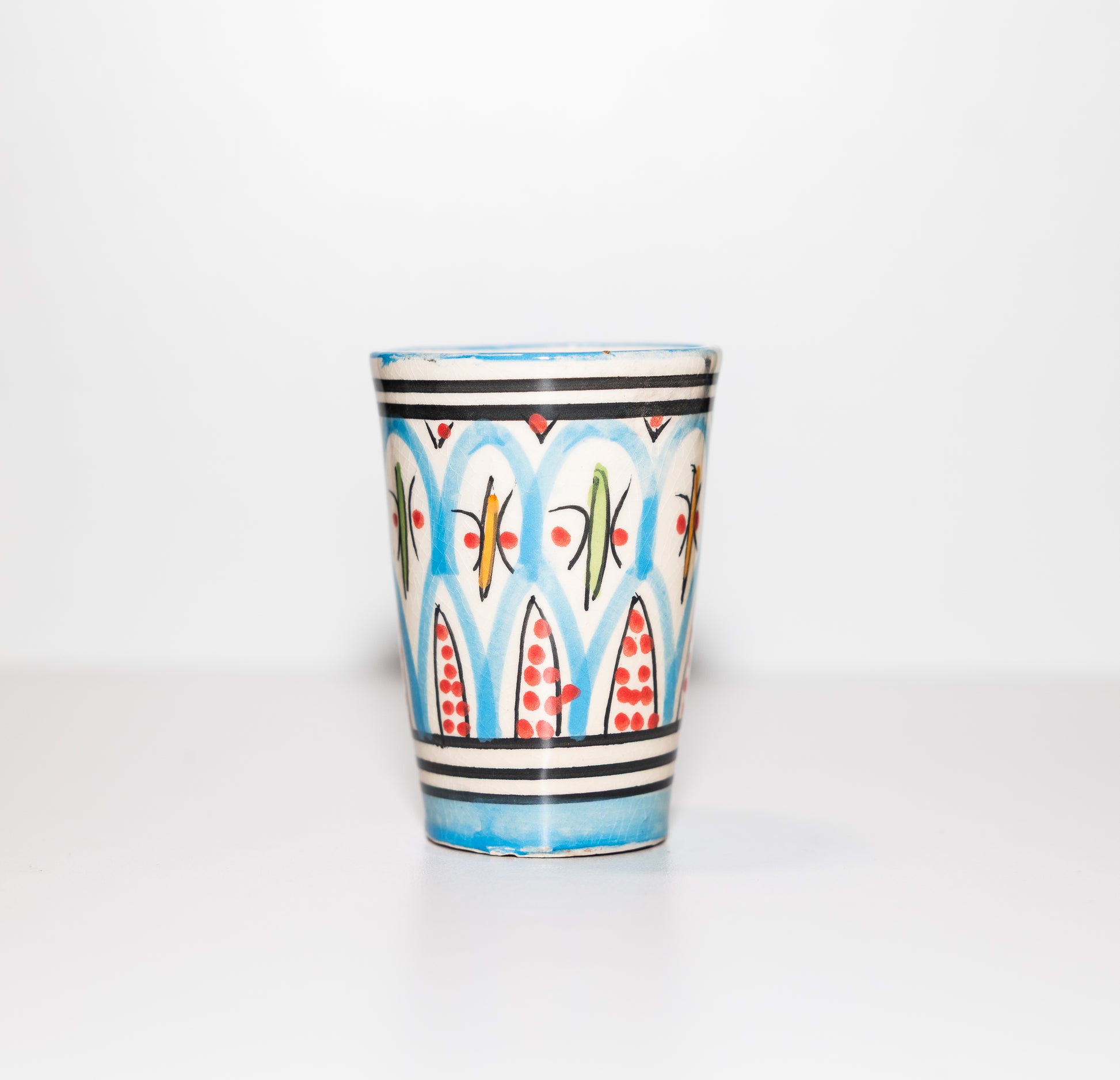 Verre en céramique marocain peint à la main, motif zellige classique, couleur bleue avec accents rouges et noirs.